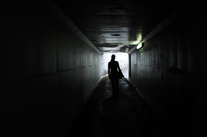 Silhouette of a young woman walks alone in a dark tunnel. Violence against women concept. Real people, copy space